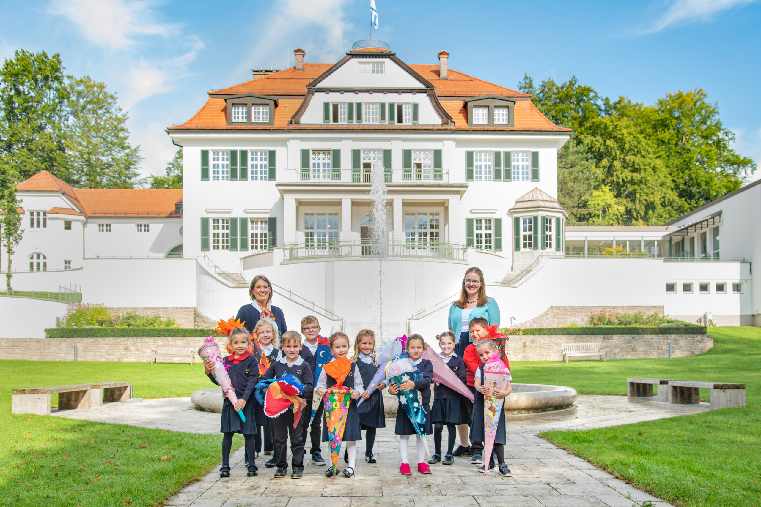 Die neuen Schülerinnen und Schüler der ersten Klasse der privaten Grundschule Eggenberg am Brunnen vor der Villa Eggenberg, mit ihren zwei Lehrerinnen.
